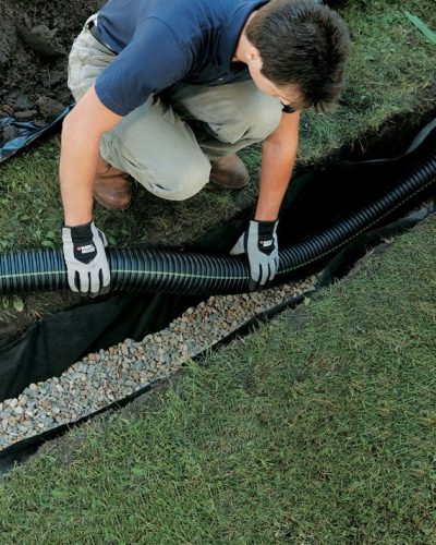 water control technician installing water egress tube for french drain